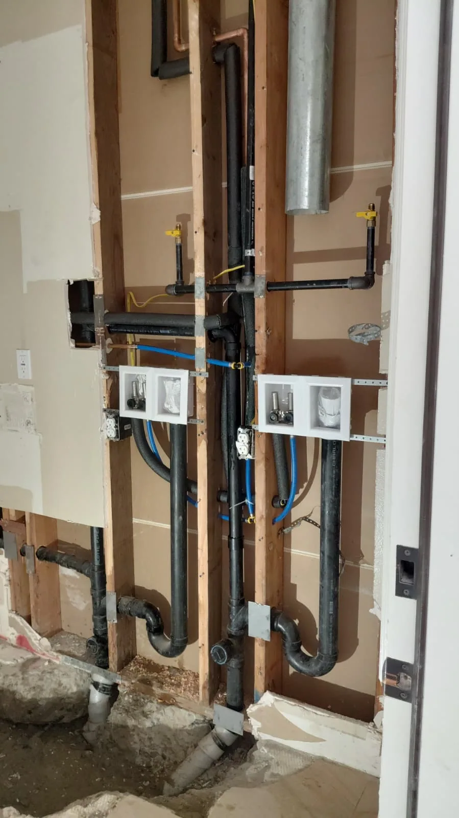 Exposed bathroom water supply pipes and drain rough-in during plumbing work